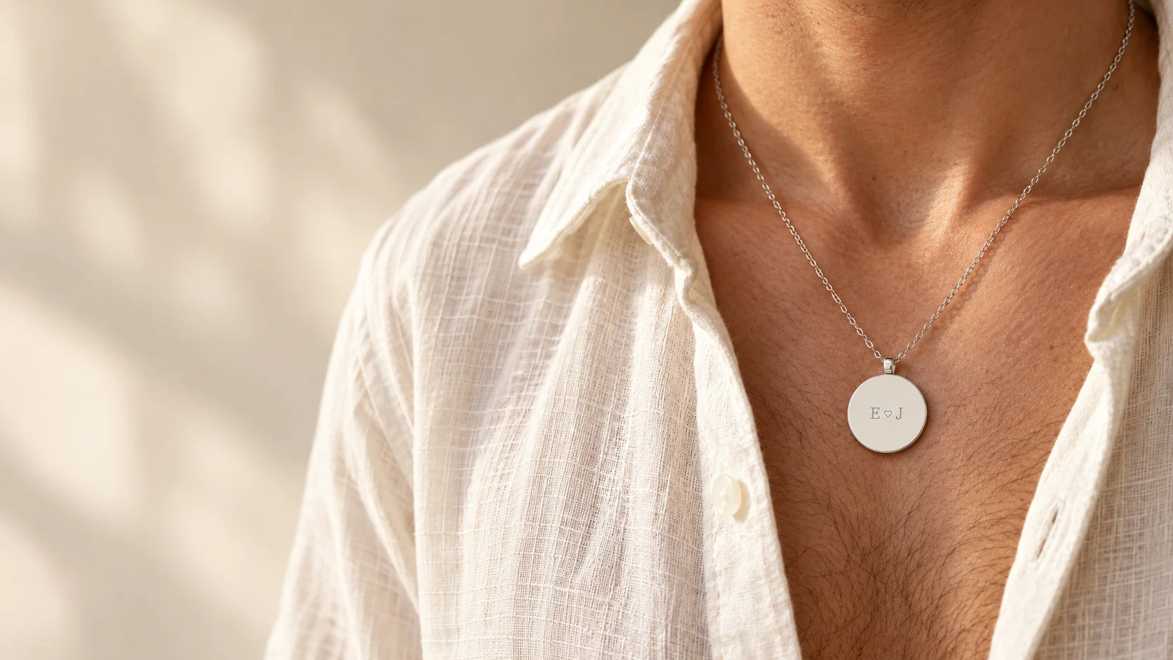 Silver initials pendant worn with an open ivory linen shirt
